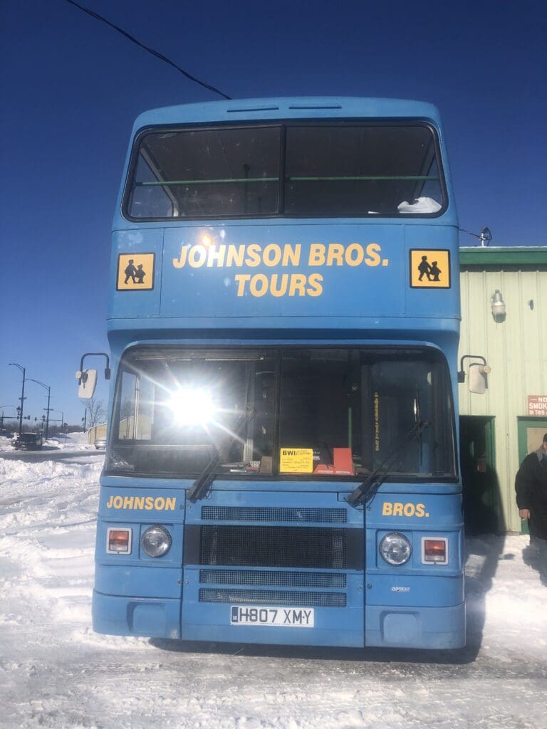 A blue double decker bus parked in the snow.