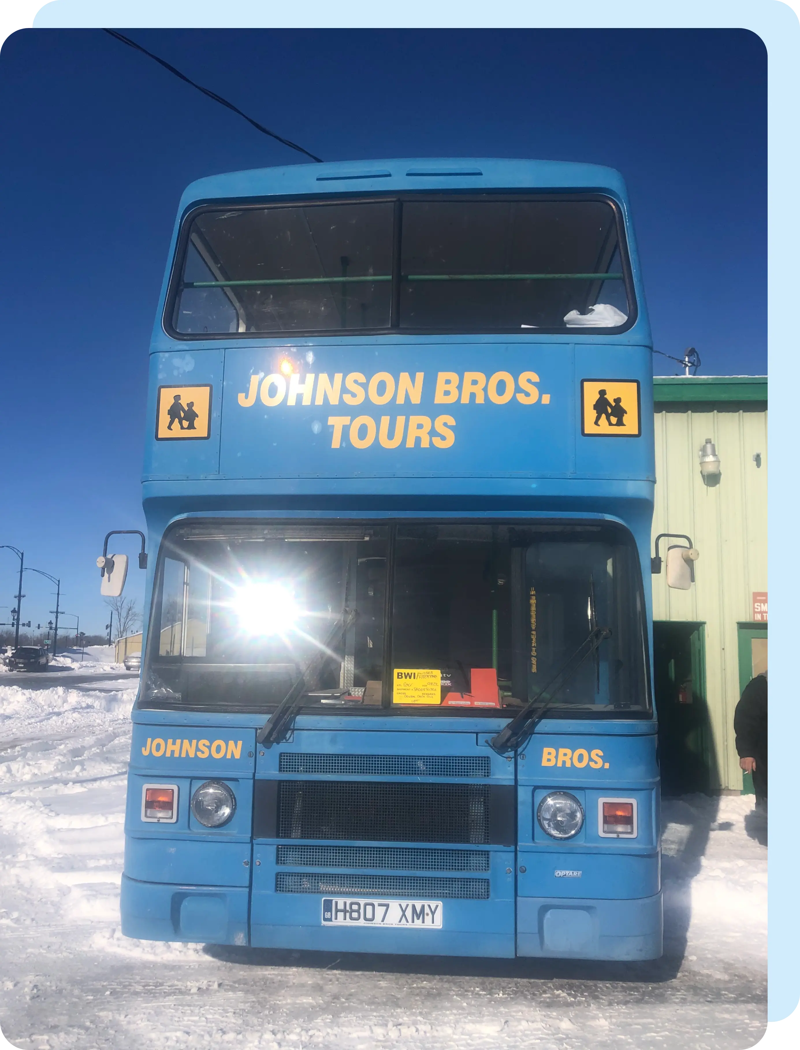 A blue double decker bus is parked in the snow.