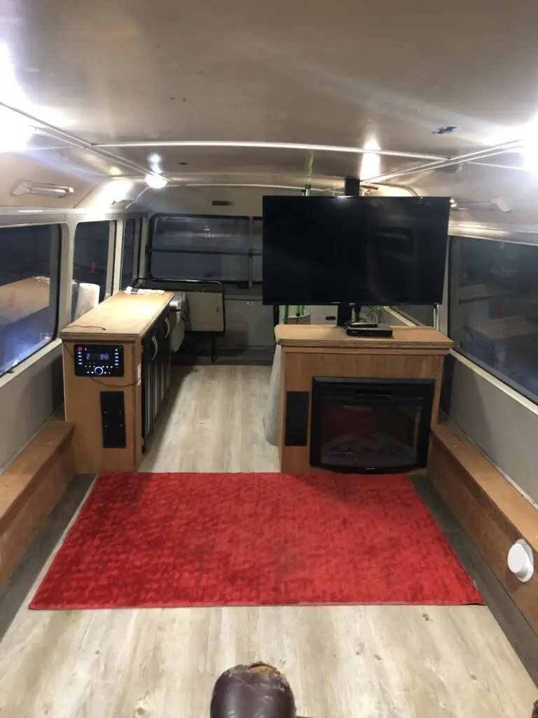 A large room with two tvs and a red rug.