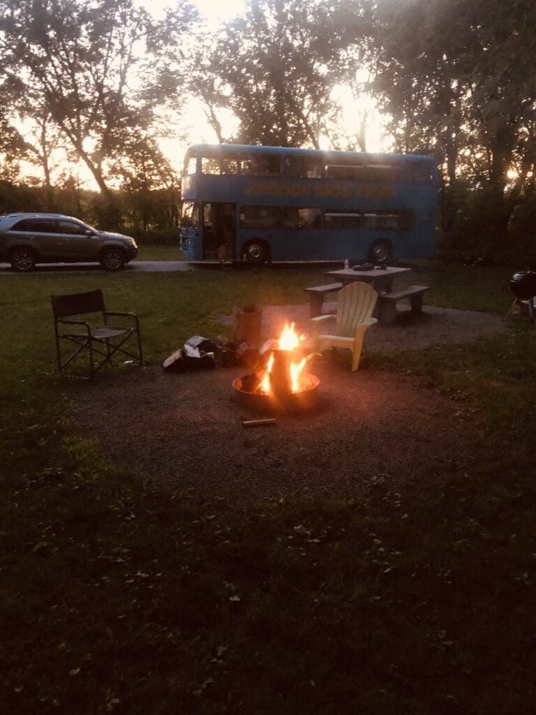 A fire pit with chairs and a bus in the background.