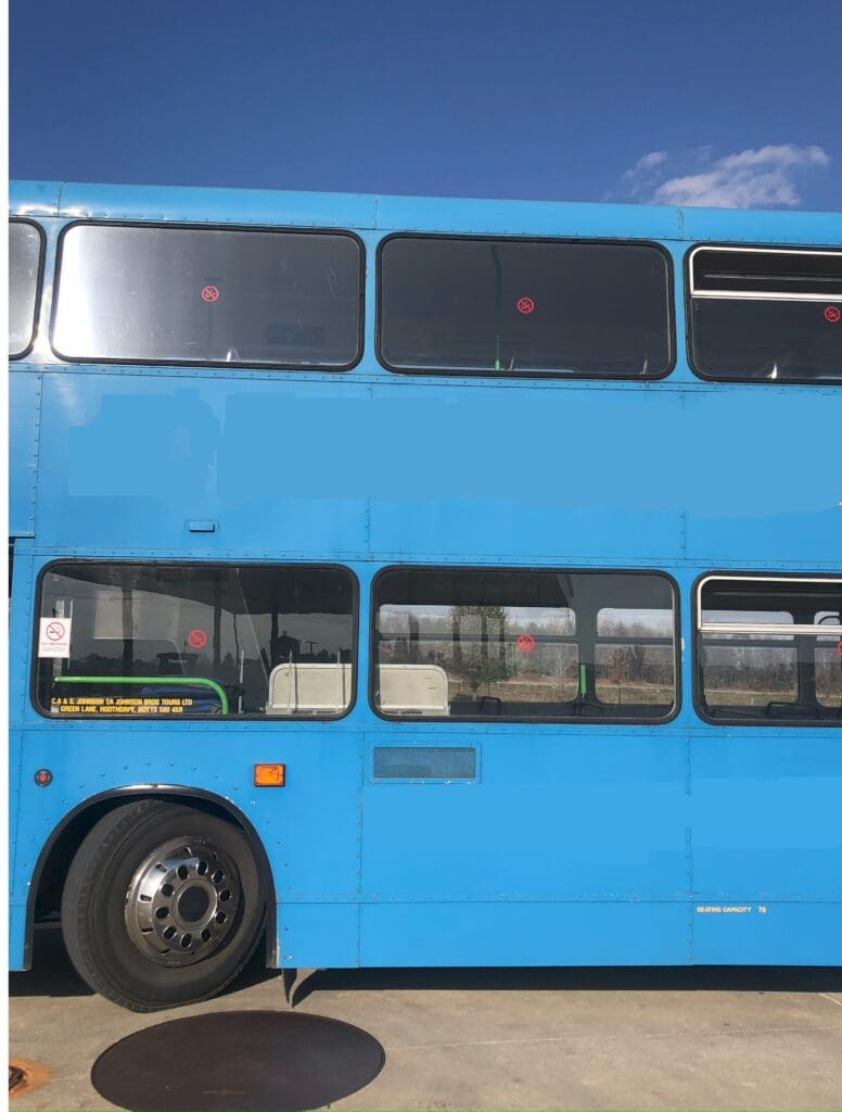 A blue double decker bus is parked in front of the sky.