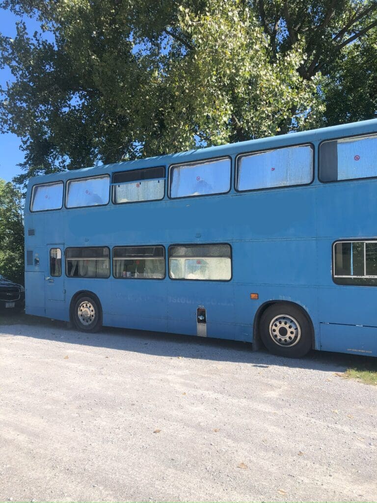 A blue double decker bus parked in the parking lot.