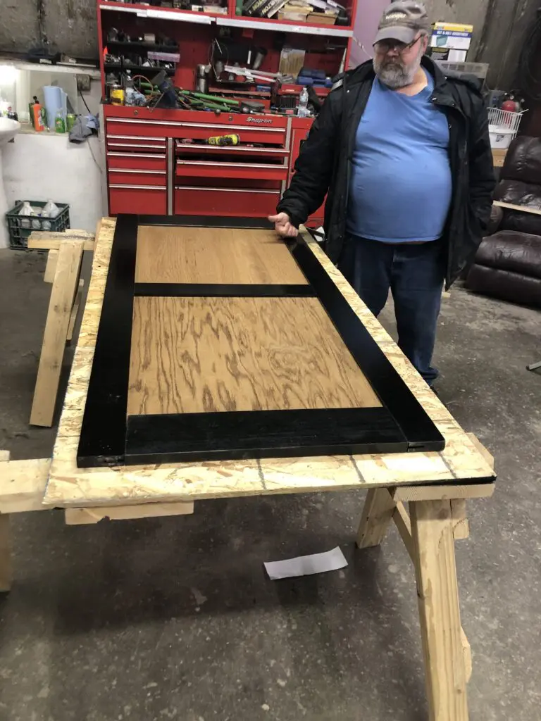 A man standing next to a table with black trim.