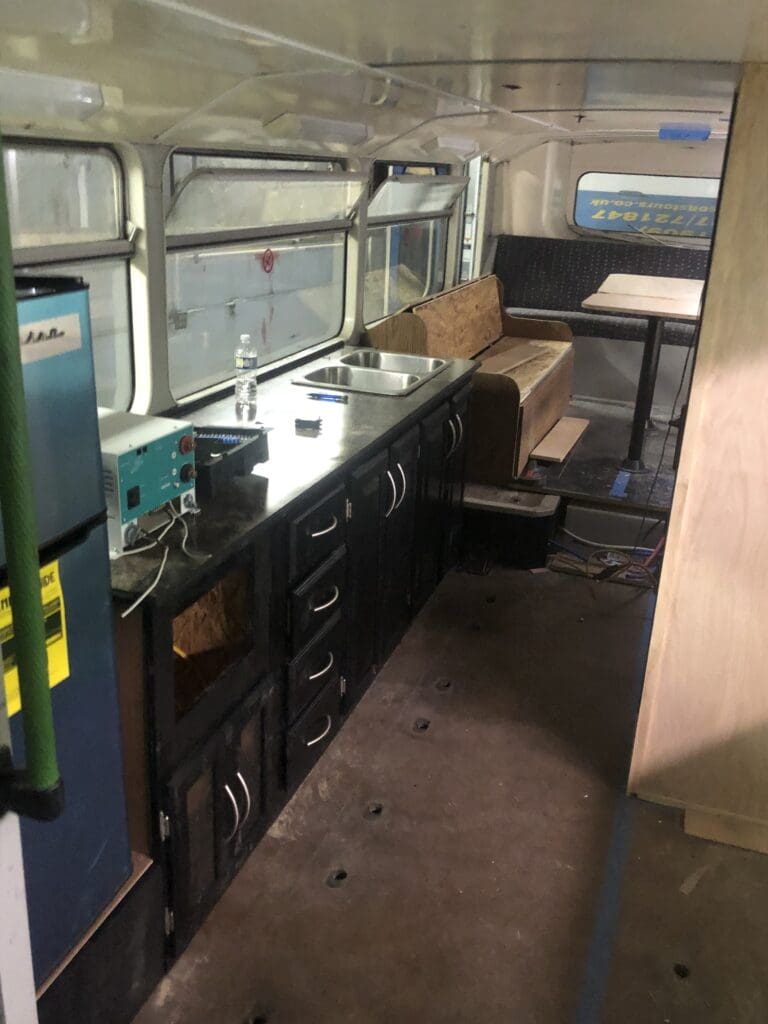 A kitchen with black cabinets and a refrigerator.