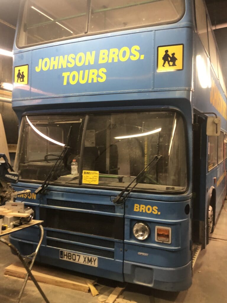 A blue double decker bus parked in a building.