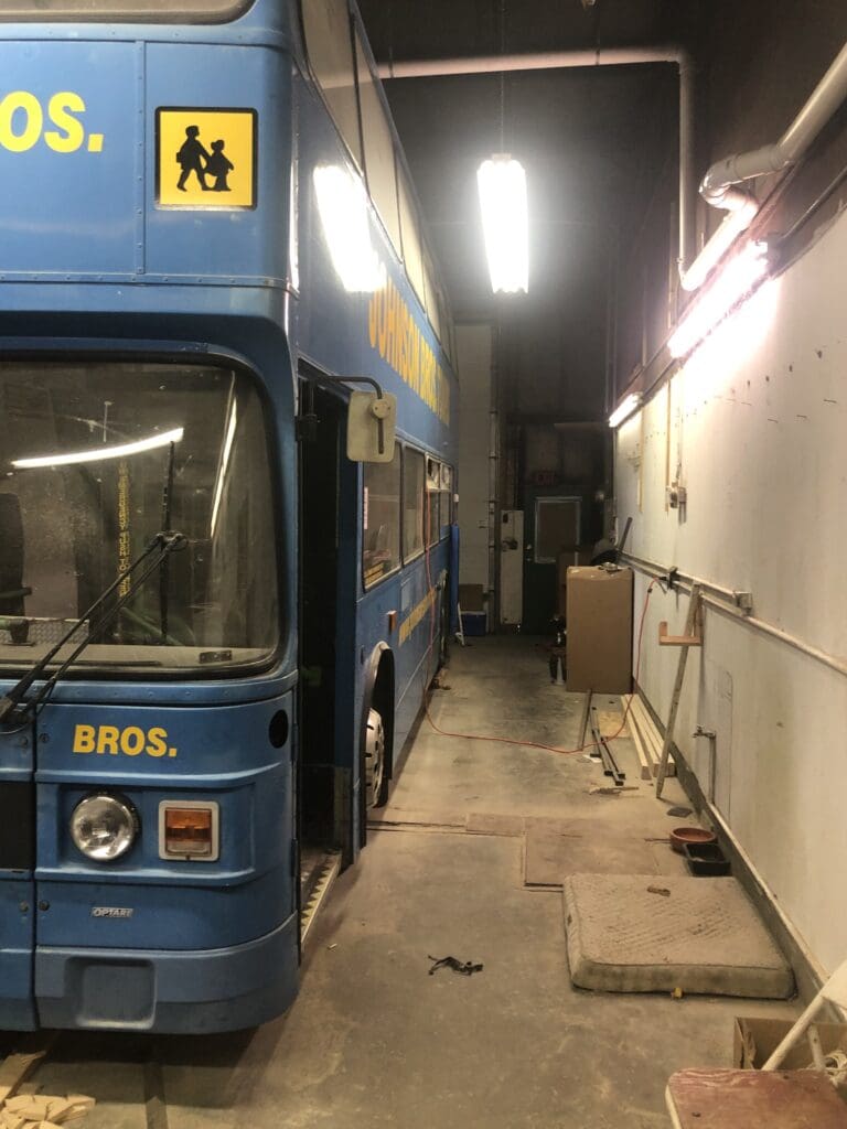 A blue bus parked in an alley way.