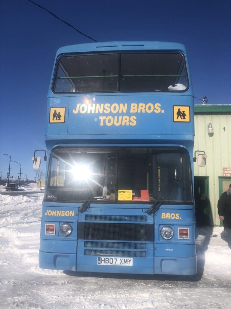 A blue double decker bus parked in the snow.