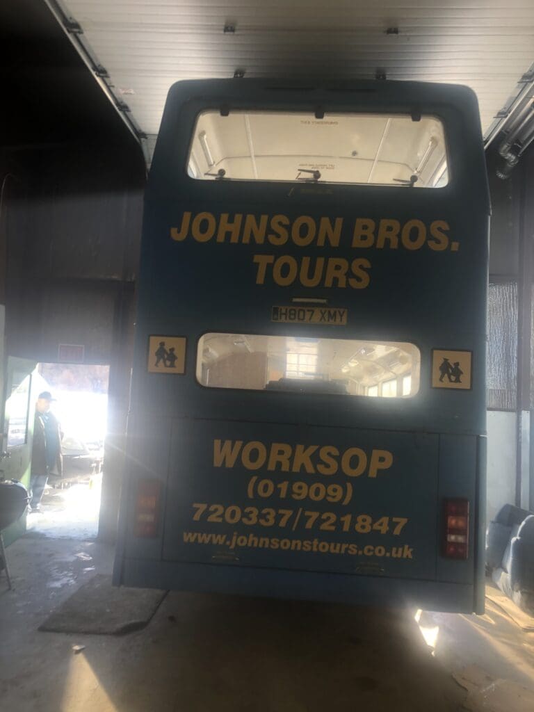 A blue and yellow bus is parked in the garage.